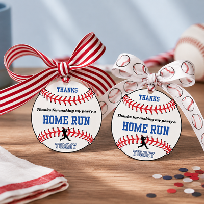 Two baseball-themed party favor tags with ribbons on a wooden surface.